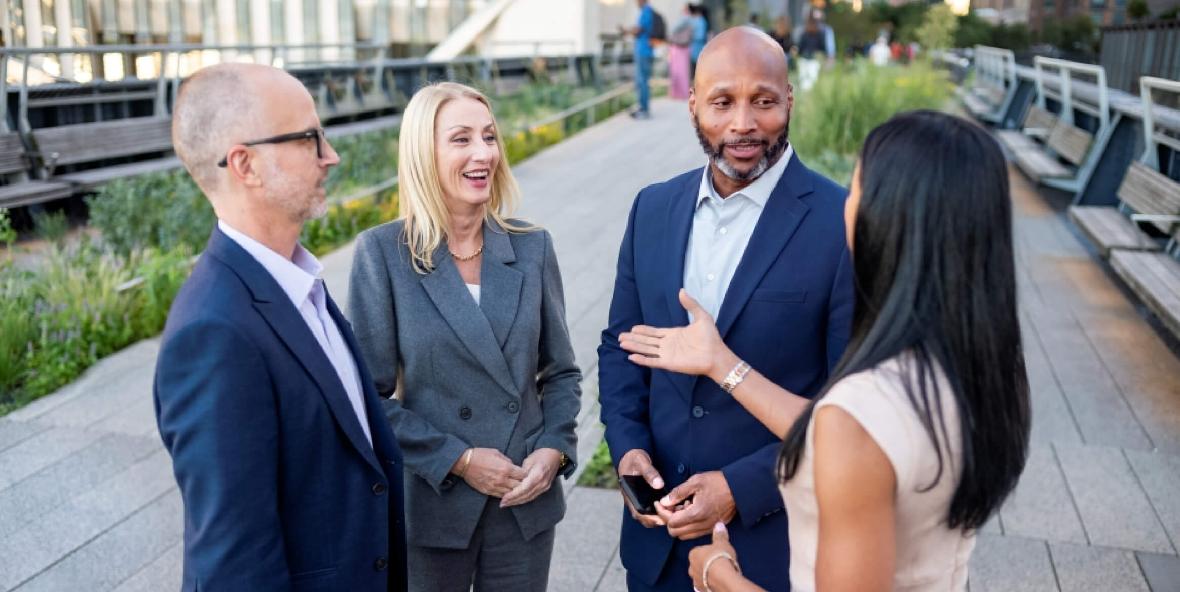 Businesspeople converse outside in a courtyard.